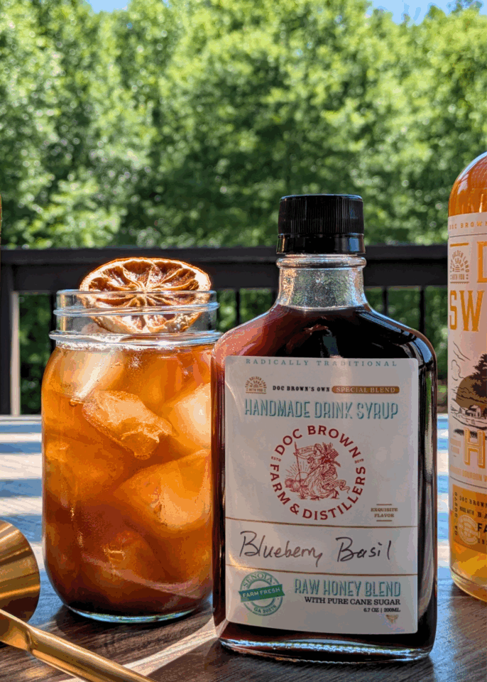 A bottle of handmade syrup next to a cocktail.